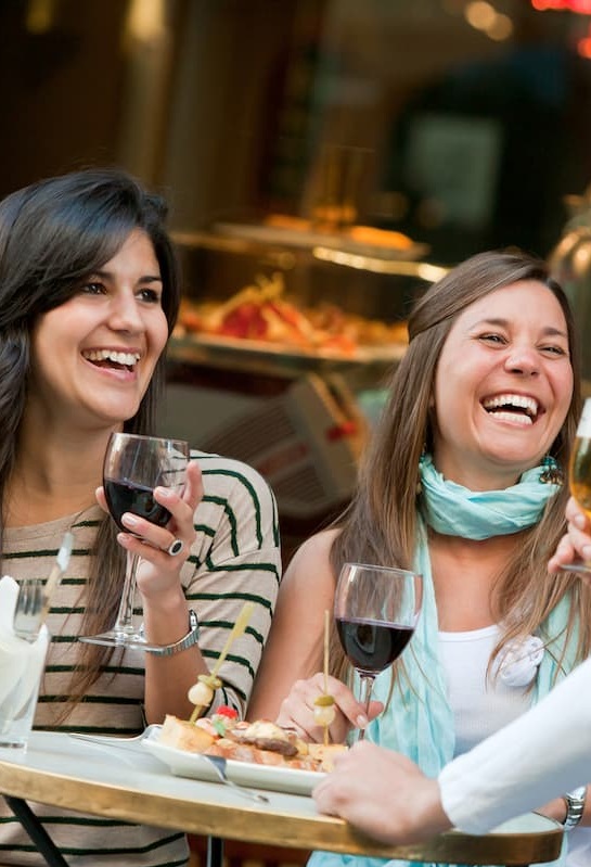 two women laughing holding wine with tapas