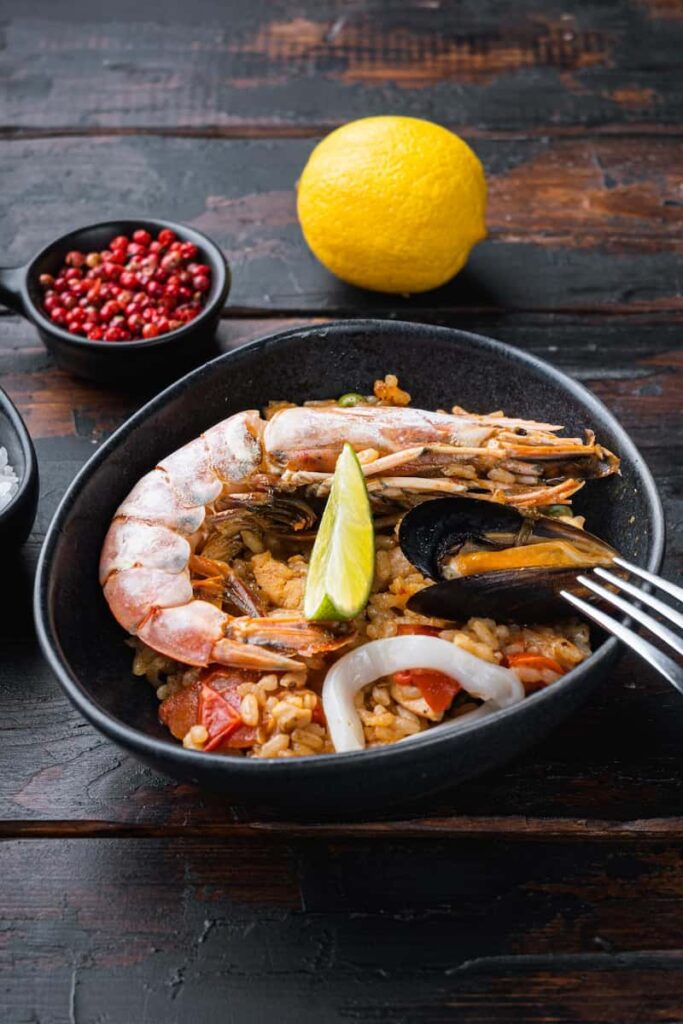 Sea food specialties paella in bowl on old dark wooden table in Palo Cortao. One of the best Paella in Barcelona.