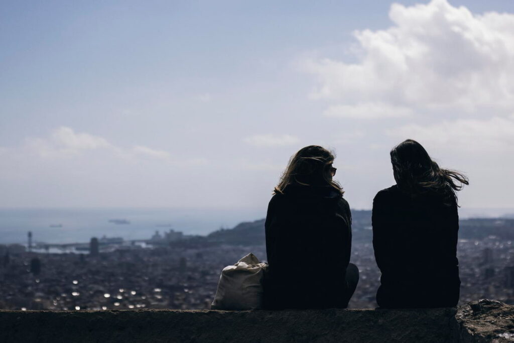 Girls talking and looking at Barcelona cityscape from a viewpoint in Bunkers del Carmel. one of the best views in Barcelona bunkers.