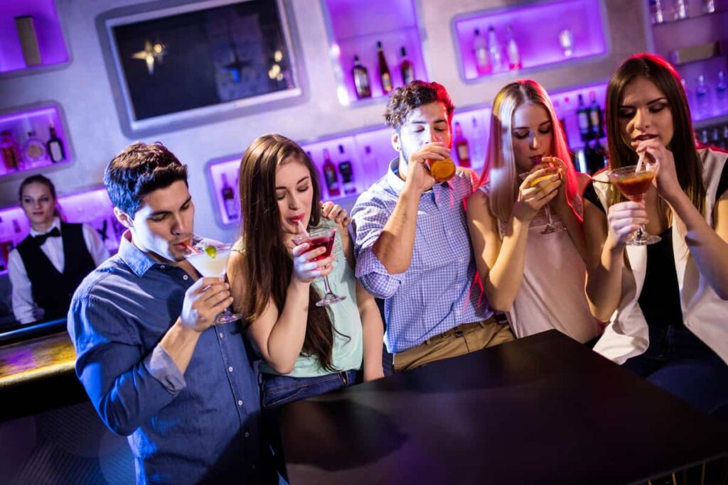 Group of friends having cocktail at bar counter in barcelona adult only hotel