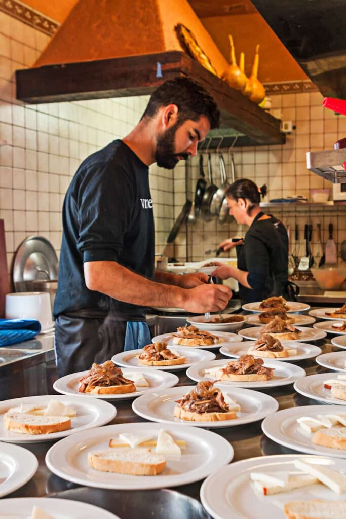 Waiter prepare meals for customers on Tosca. One of the best Barcelona tapas restaurants.