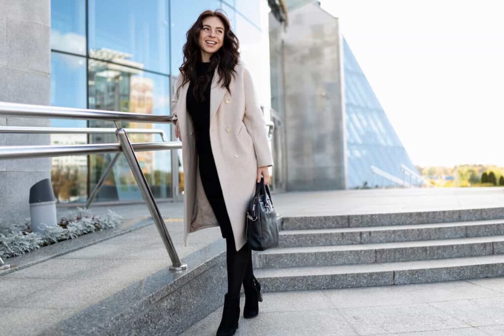 portrait of a european woman model in a coat on the background of a business center in barcelona fashion