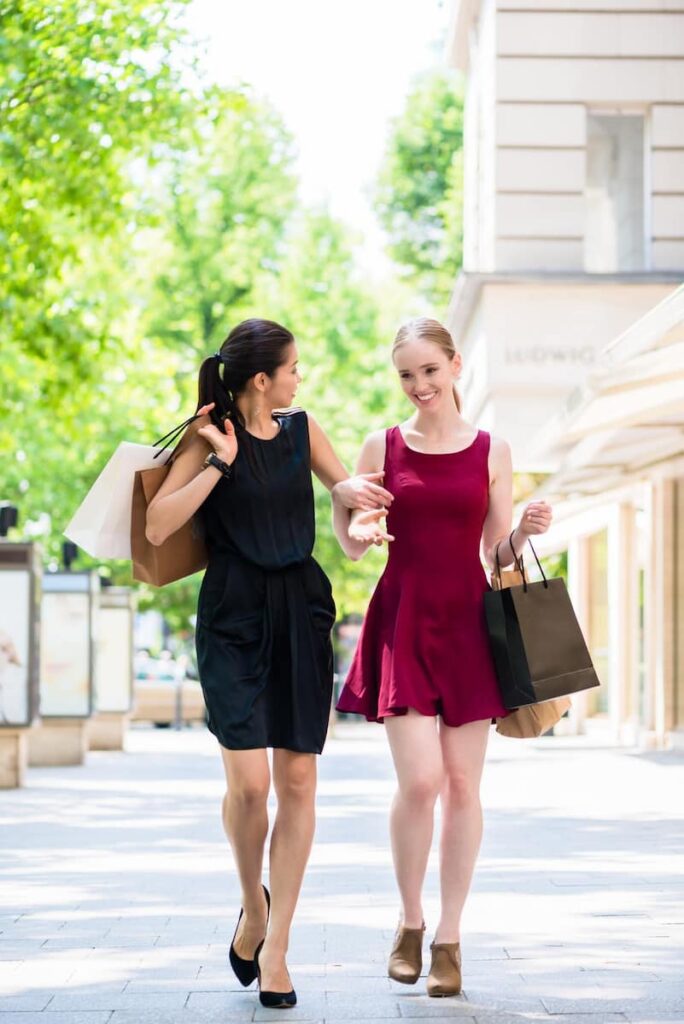 Two female happy walking to the streets after shopping in Carrer Major de Sarrià. One of the best luxury shopping in Barcelona.