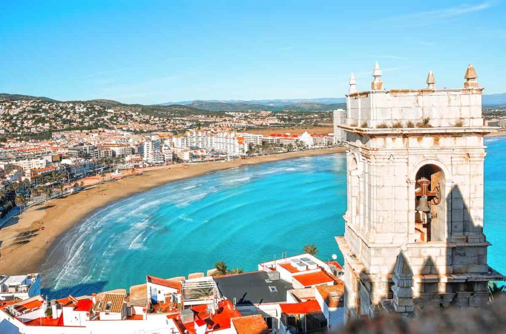Panoramic view of the beach and old bell tower in Peñíscola, a coastal gem that's often listed among the top seaside Spanish towns to visit