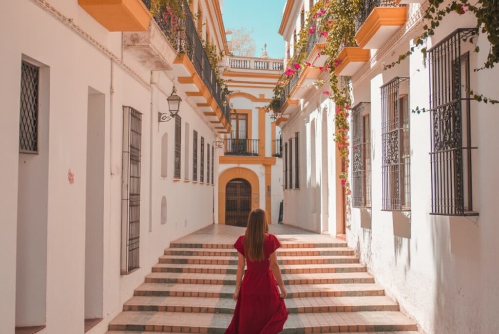 Woman in a red dress walking up steps through a whitewashed street in one of the best towns to visit on the Costa del Sol