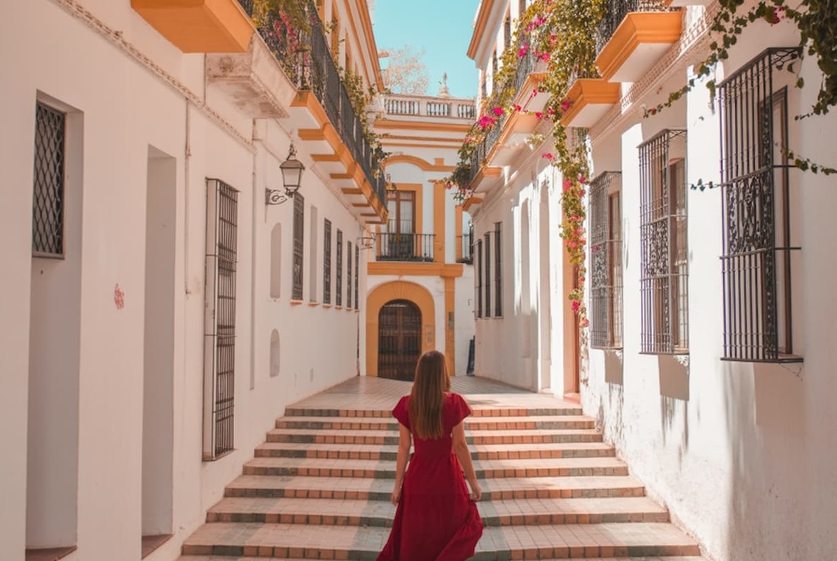 Woman in a red dress walking up steps through a whitewashed street in one of the best towns to visit on the Costa del Sol