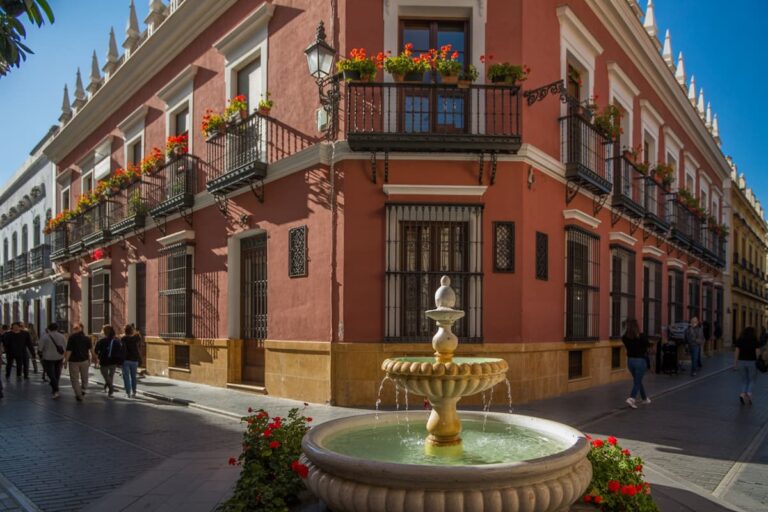 A charming fountain sits in front of a flower-covered building on a peaceful street in Seville, capturing the relaxed pace of a ten day itinerary in Spain