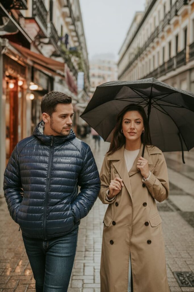 a couple in wet weather clothes walking down a street in Madrid, ready for fall and winter in Spain