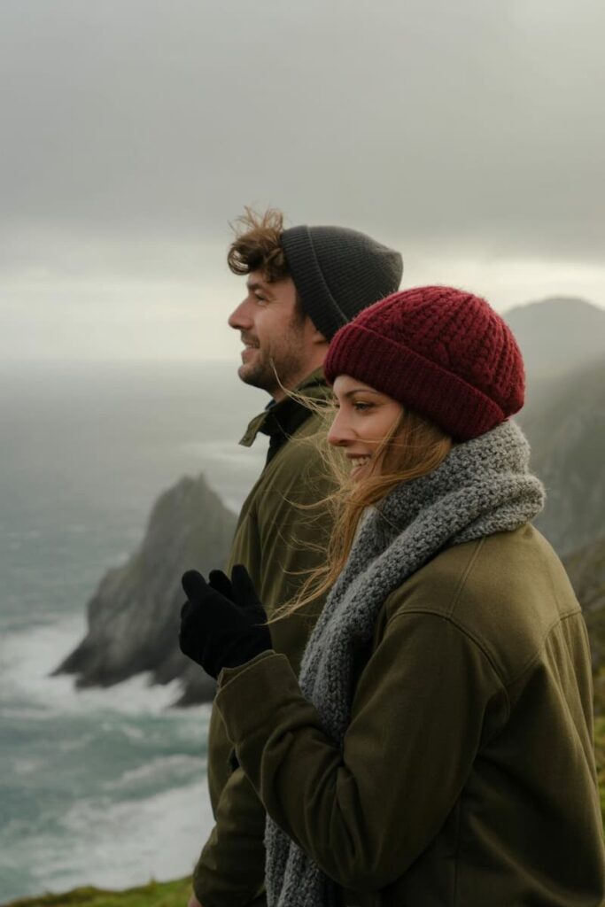 a couple in winter clothes looking over the ocean from a viewpoint in Spain